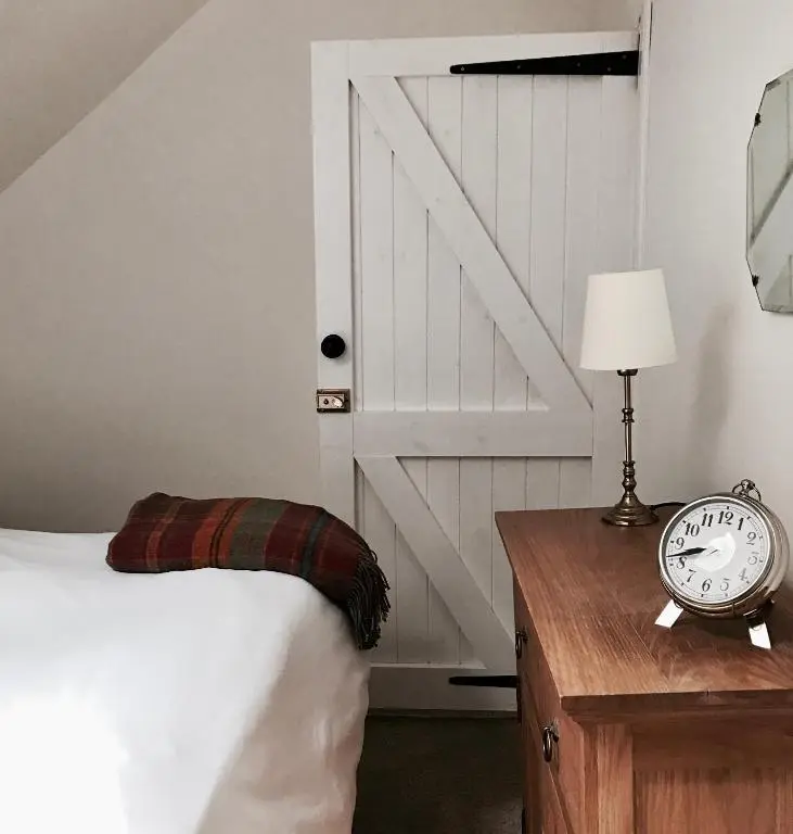 a bedroom with a bed and a door and a clock at Dandaleith Cottage No.2 in Craigellachie