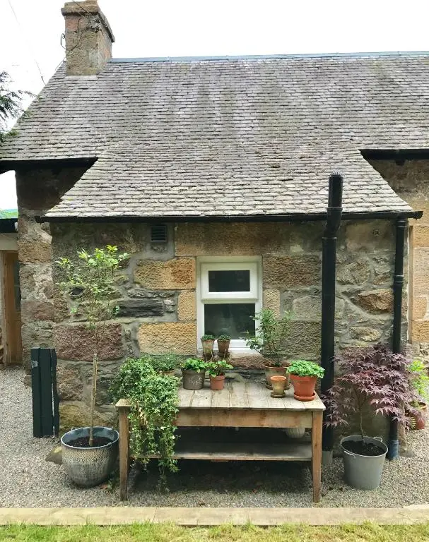 a small stone house with potted plants on a table at Dandaleith Cottage No.2 in Craigellachie