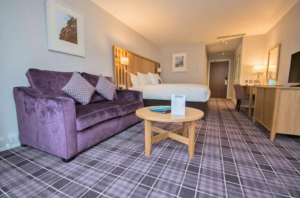 a hotel room with a couch and a bed at Kingsmills Hotel in Inverness