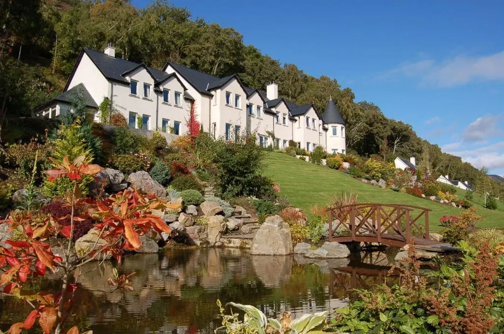 a large house on a hill with a pond and a bridge at Loch Ness Lodge in Drumnadrochit