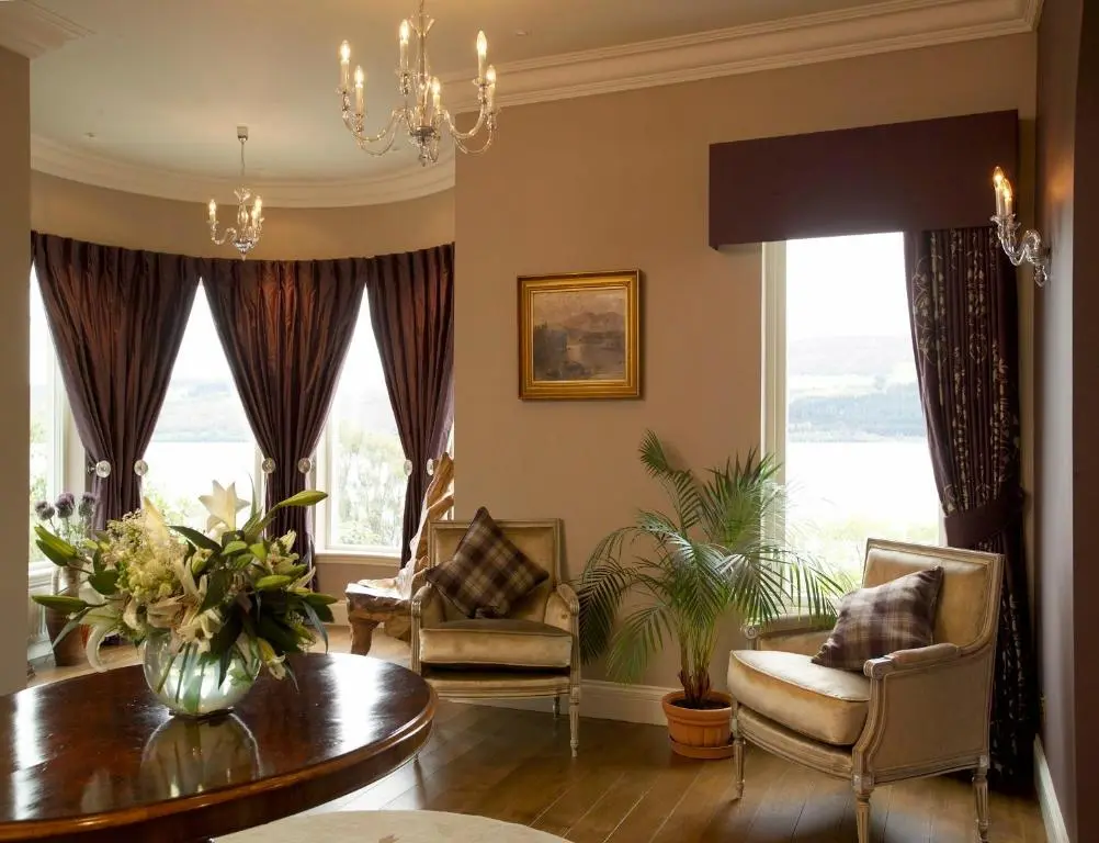 a living room with a table and chairs and windows at Loch Ness Lodge in Drumnadrochit