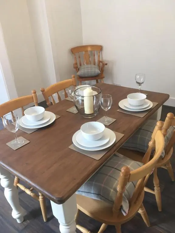 a wooden table with plates and wine glasses on it at Whisky Cottage in Inverness