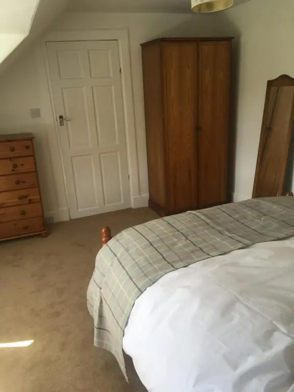 a bedroom with a bed and a wooden dresser at Whisky Cottage in Inverness