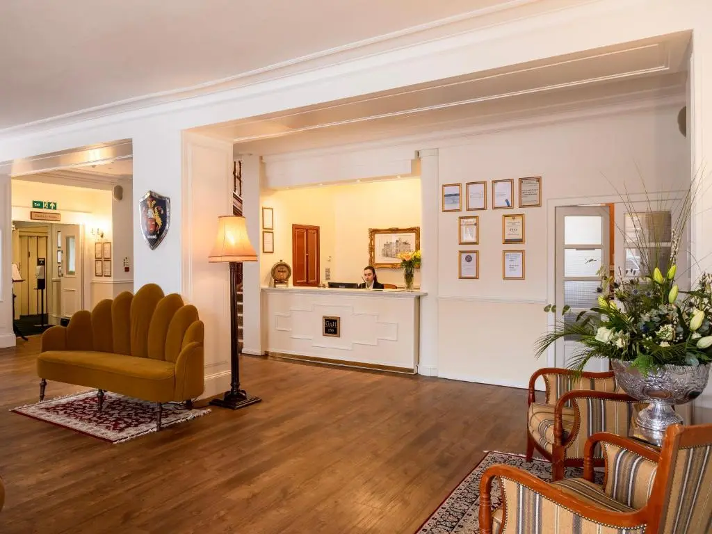 a living room with a yellow chair and a table at Grant Arms Hotel in Grantown on Spey