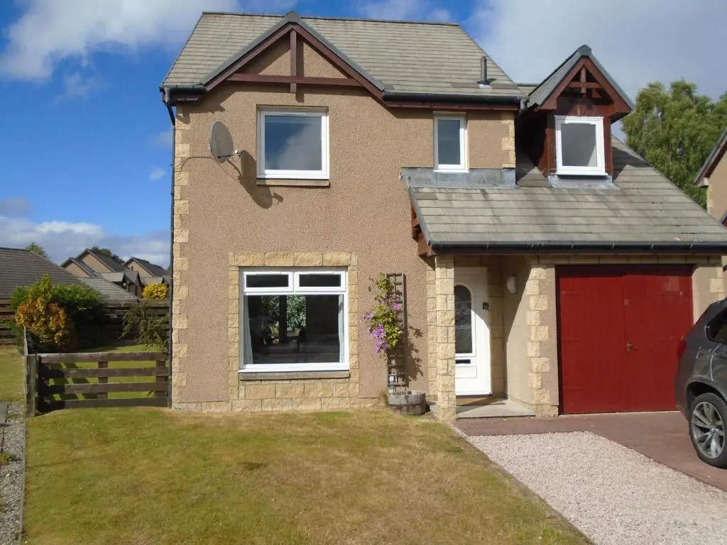 a brown brick house with a red garage at White Corries in Aviemore