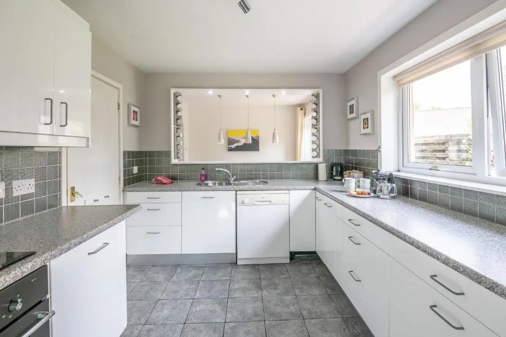 a kitchen with white cabinets and a sink at White Corries in Aviemore