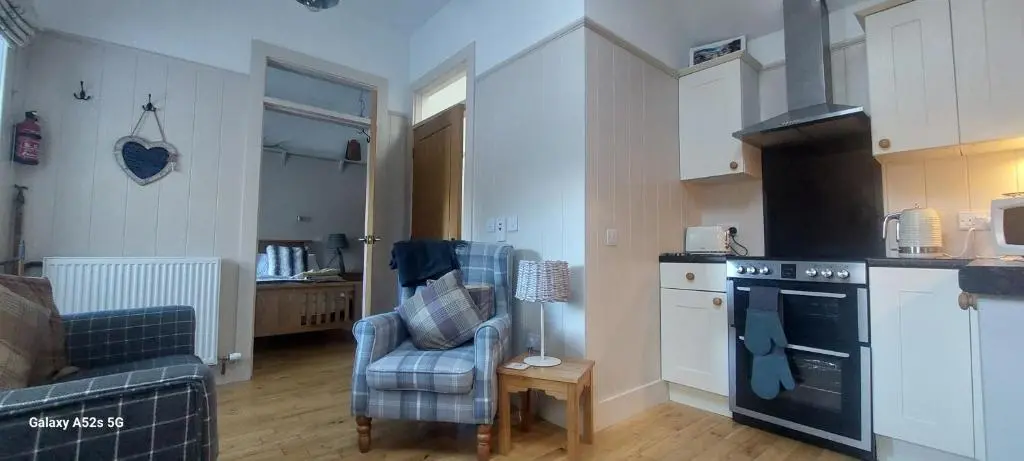 a kitchen with a stove and a chair in a room at Fairdene Cottage in Ballater