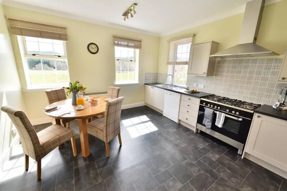 a kitchen with a table and chairs and a stove at Knocklea in Alness