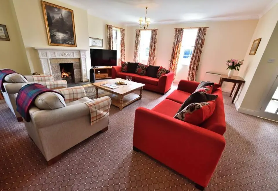 a living room with red furniture and a fireplace at Knocklea in Alness