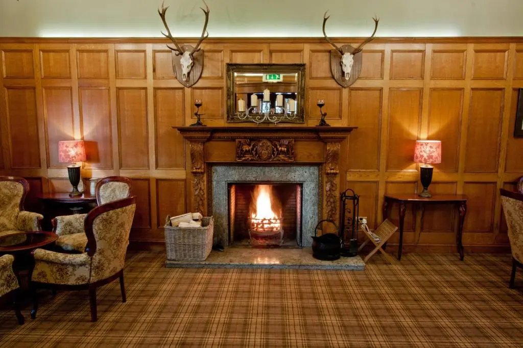 a living room with a fireplace with antlers on the wall at Duke Of Gordon Hotel in Kingussie