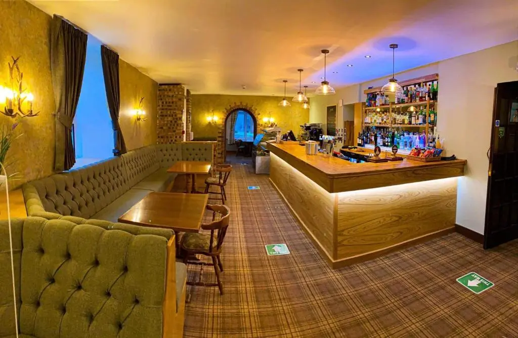a bar with a couch and tables in a room at Duke Of Gordon Hotel in Kingussie
