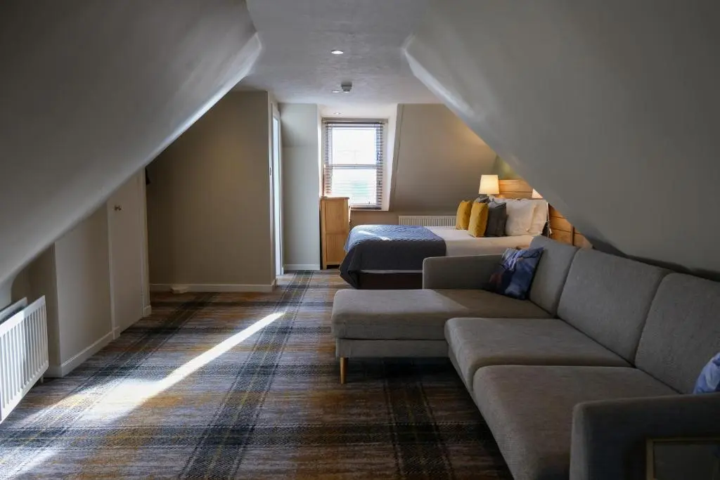 a living room with a couch and a bed at Glen Mhor Hotel at Uile-bheist 'Brewstillery' in Inverness