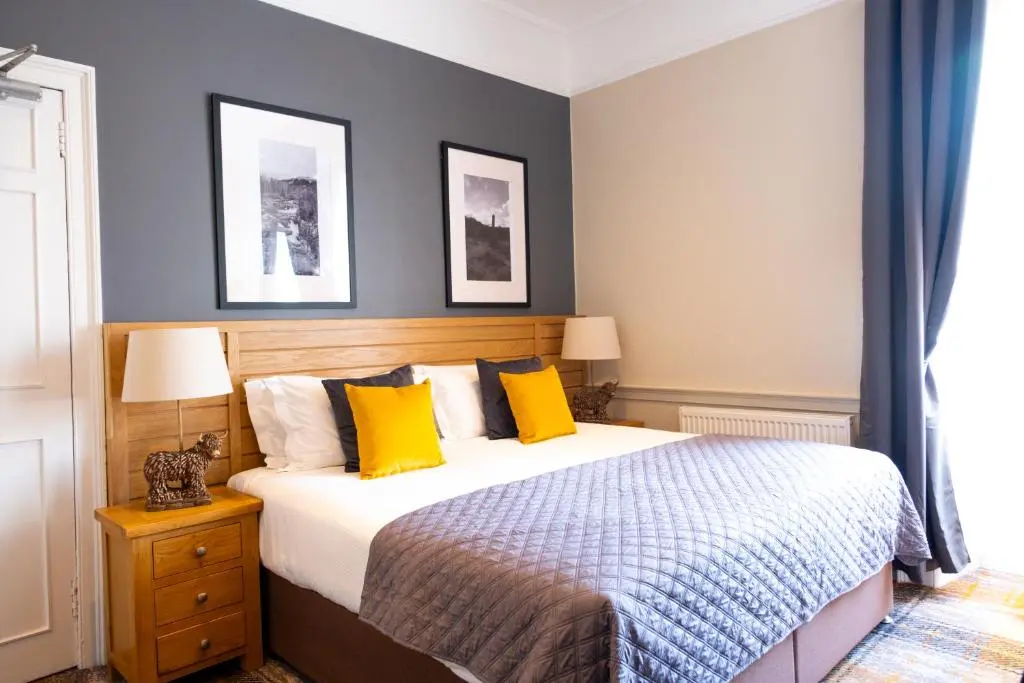 a bedroom with a bed with yellow pillows at Glen Mhor Hotel at Uile-bheist 'Brewstillery' in Inverness