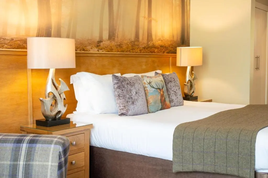 a hotel room with a bed and two lamps at Glen Mhor Hotel at Uile-bheist 'Brewstillery' in Inverness