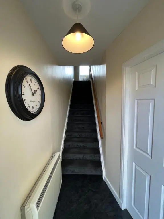 a hallway with a clock and a stair case at Inverness House in Inverness