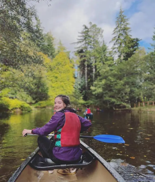 a woman in a canoe on a river at Fairburn Activity Centre in Contin