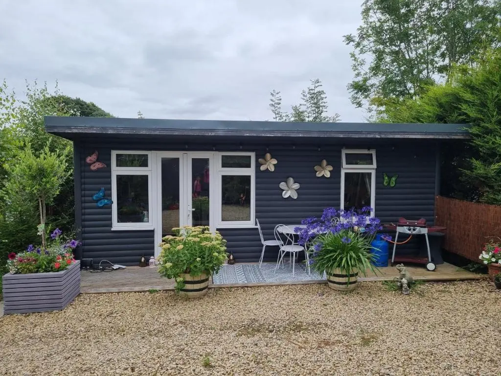 a blue tiny house with a patio and flowers at Nanny's little highland hoose in Inverness