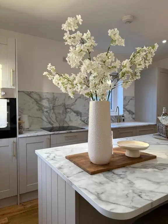 a white vase with white flowers on a counter in a kitchen at Gateway Apartment in Inverness