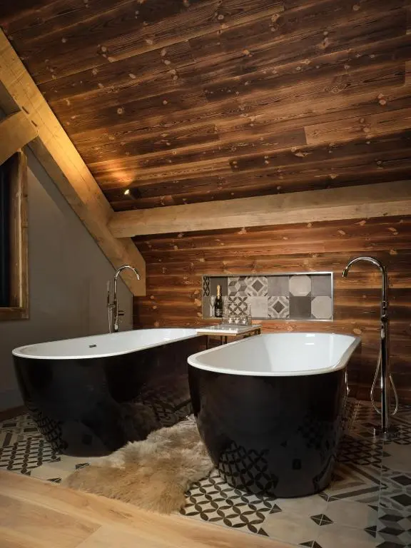 a bathroom with two tubs in a room with wooden ceilings at Macdui Lodge in Aviemore