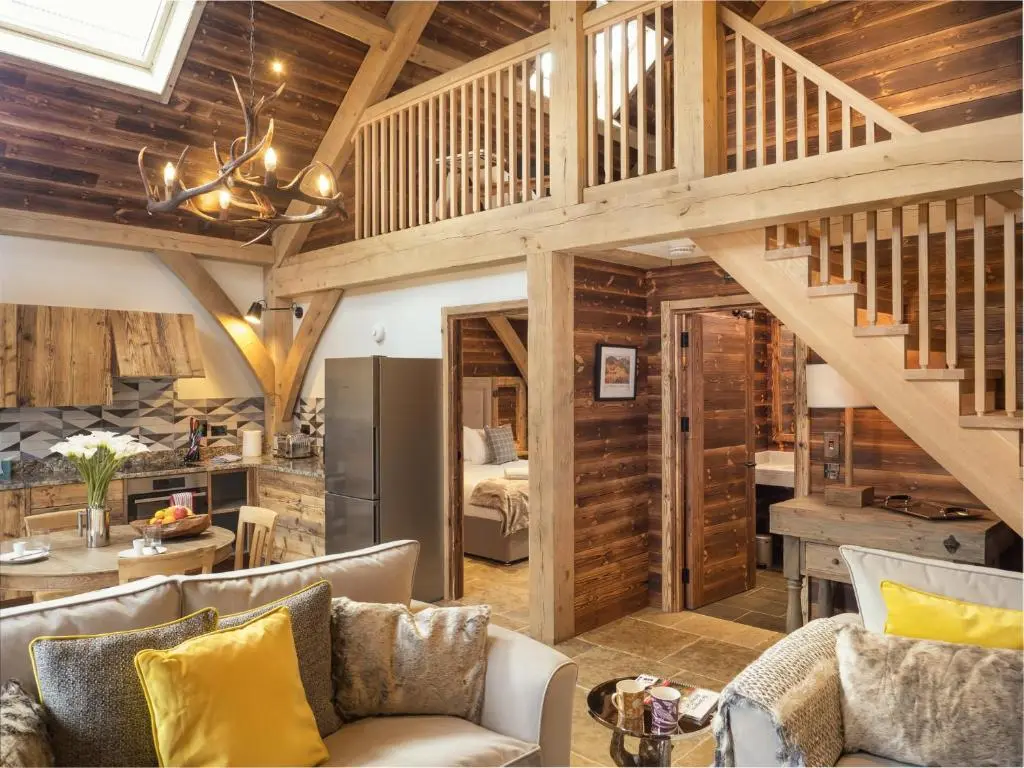 a living room with a couch and a kitchen and a staircase at Macdui Lodge in Aviemore