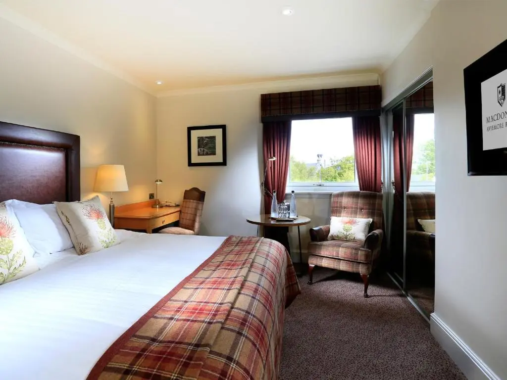 a hotel room with a bed and a chair at Macdonald Aviemore Hotel at Macdonald Aviemore Resort in Aviemore