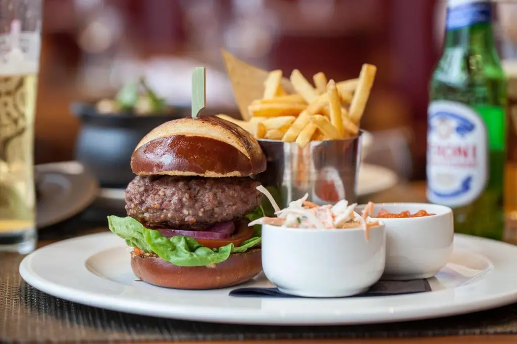 a hamburger and french fries on a plate with a drink at Macdonald Aviemore Hotel at Macdonald Aviemore Resort in Aviemore