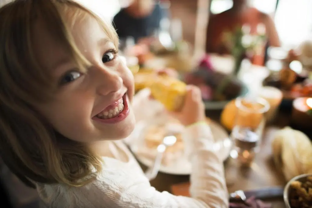 a little girl sitting at a table eating food at Macdonald Aviemore Hotel at Macdonald Aviemore Resort in Aviemore