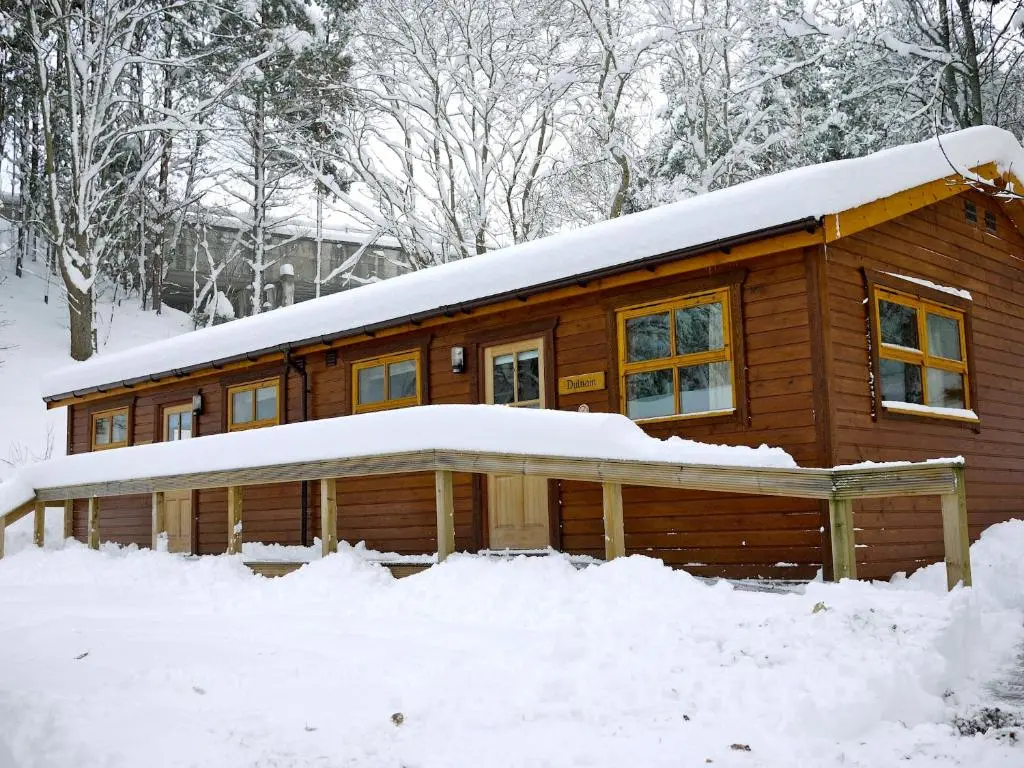 a log cabin with snow on the roof at Dulnain in Aviemore