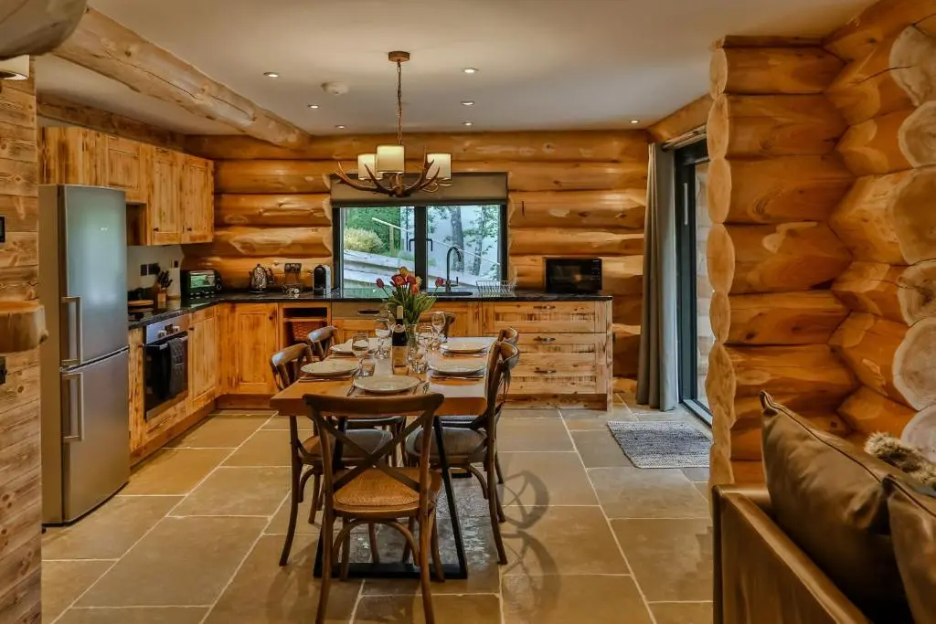 a kitchen with wooden walls and a table and chairs at Cedar Lodge in Aviemore