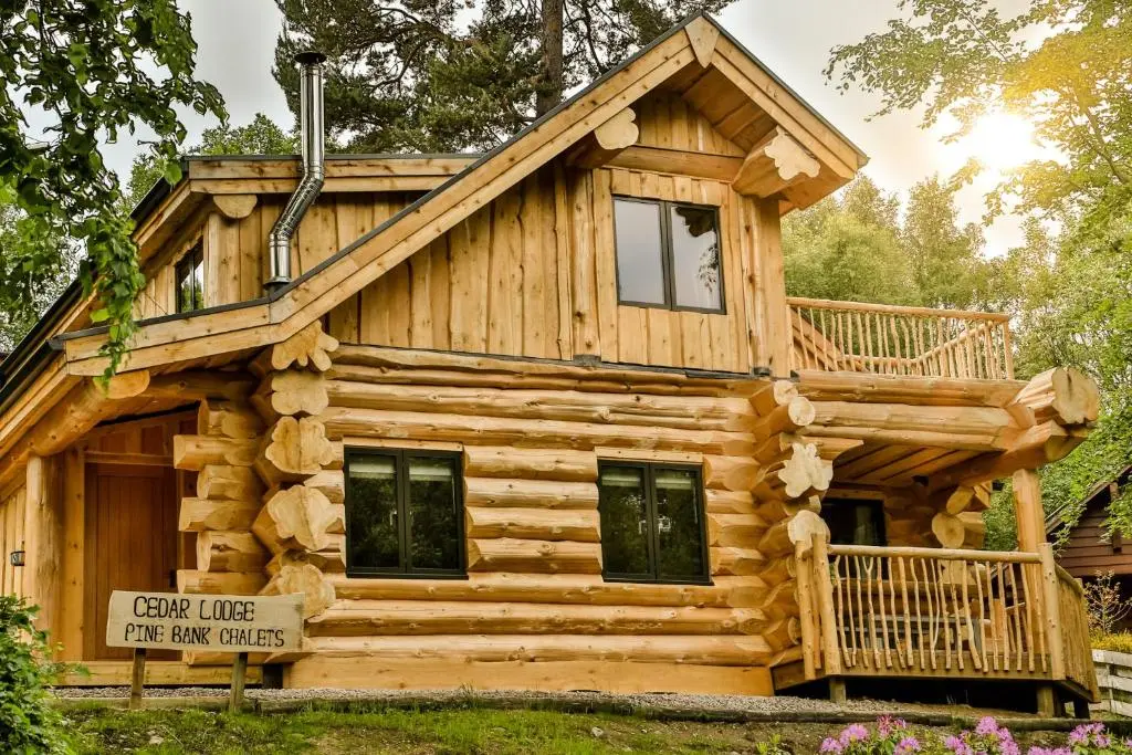 a log cabin with a wrap around porch at Cedar Lodge in Aviemore