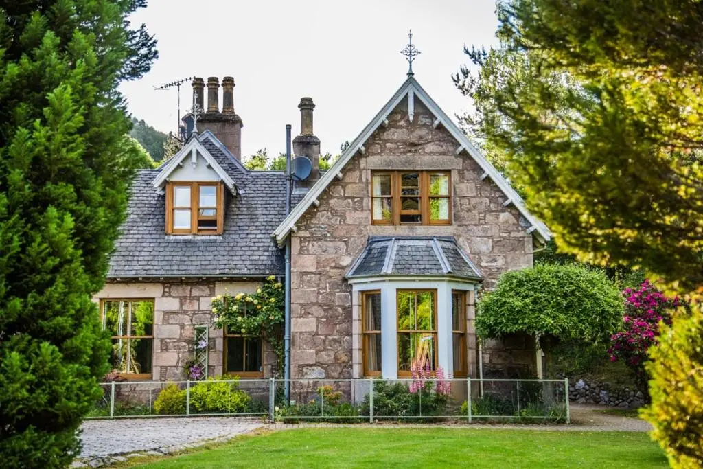 an old stone house with a fence in the yard at Shieling in Aviemore