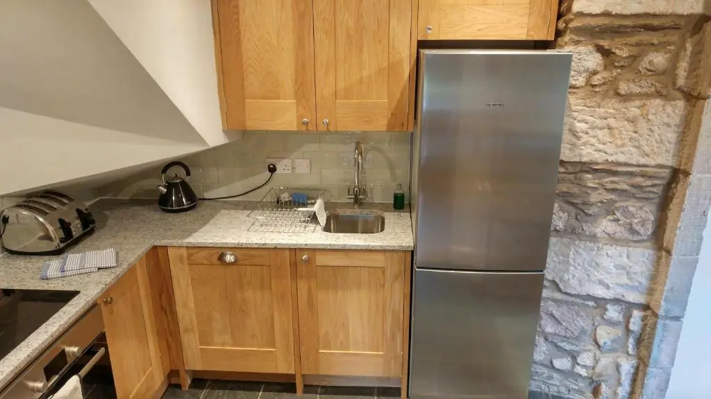 a kitchen with a stainless steel refrigerator and wooden cabinets at Shieling in Aviemore