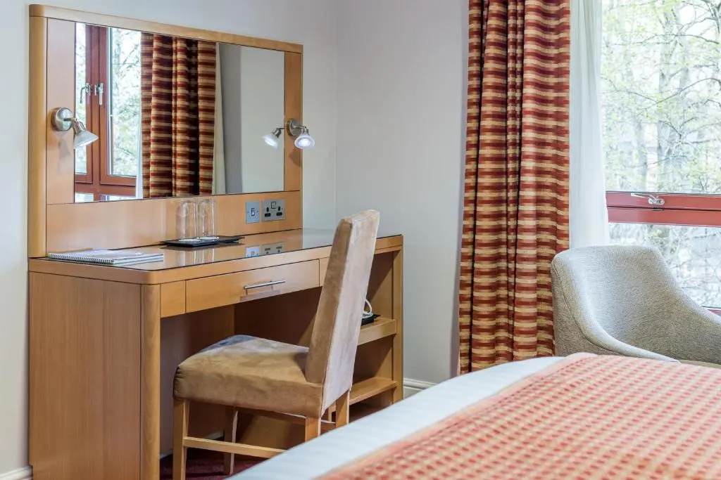 a bedroom with a desk with a mirror and a chair at High Range Lodge Hotel in Aviemore