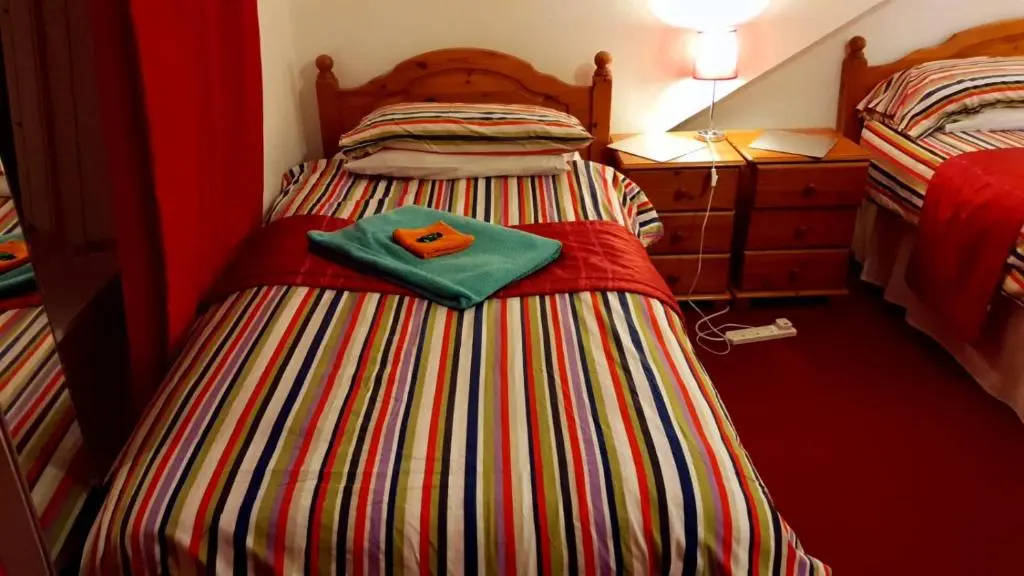 a bed with a green towel on top of it at Broomlea Guest House in Dyce