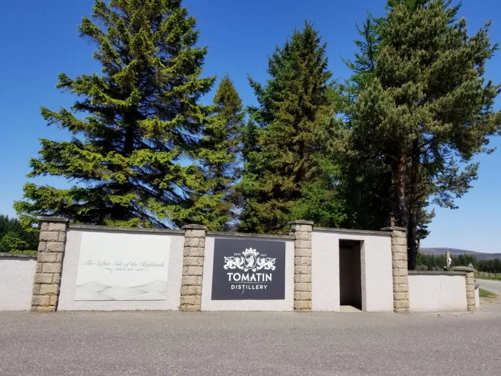 a sign in front of a building with trees in the background at Glenan Lodge Self Catering in Tomatin