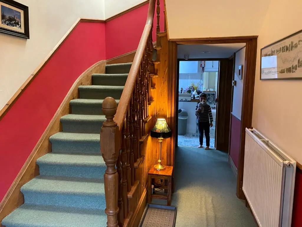 a staircase in a house with a person walking down it at Glenan Lodge Self Catering in Tomatin