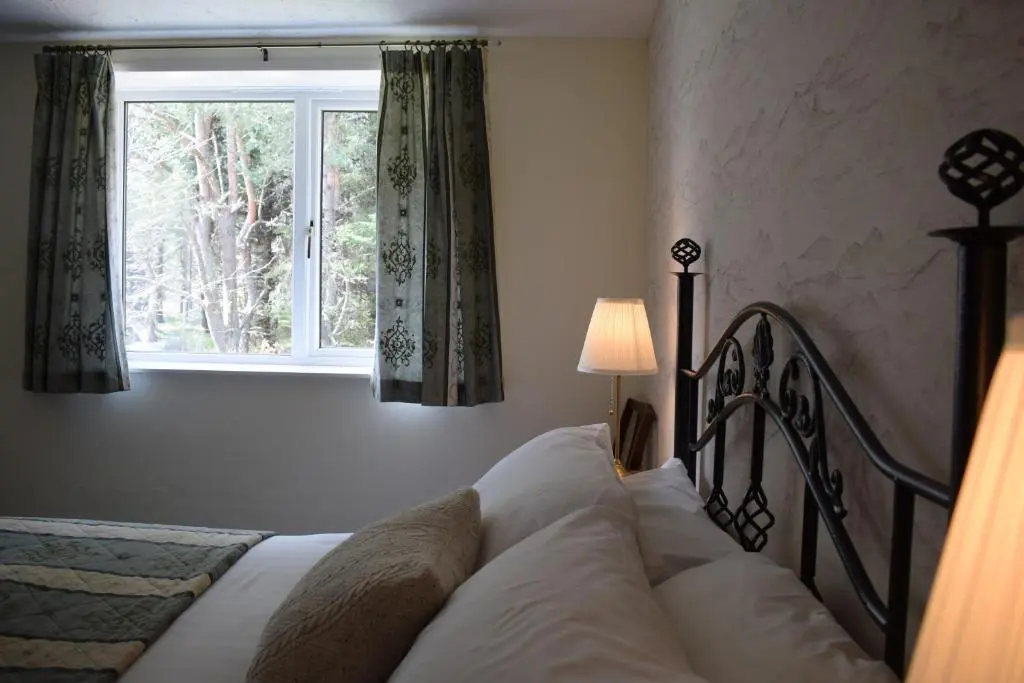 a bedroom with a bed and a window at Glenan Lodge Self Catering in Tomatin