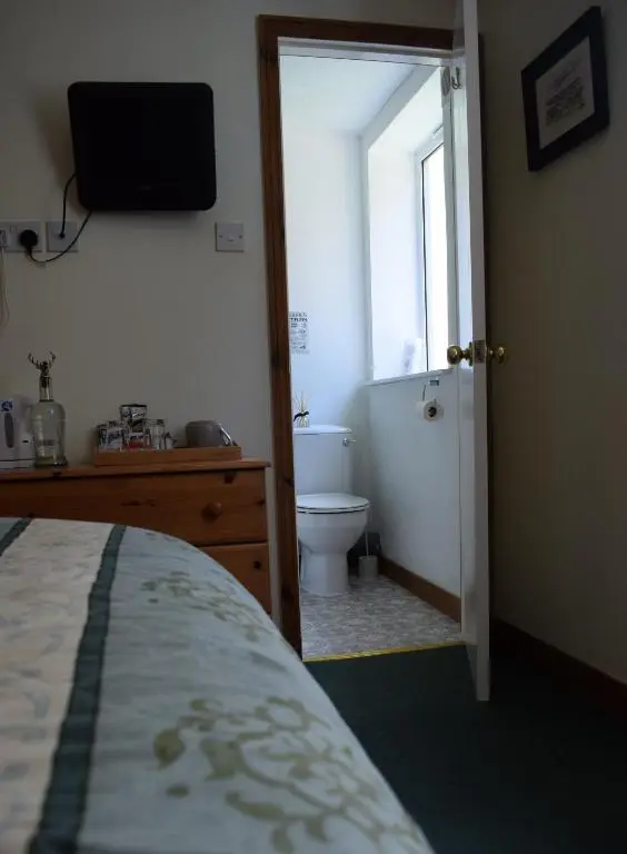 a bedroom with a bed and a bathroom with a toilet at Glenan Lodge Self Catering in Tomatin