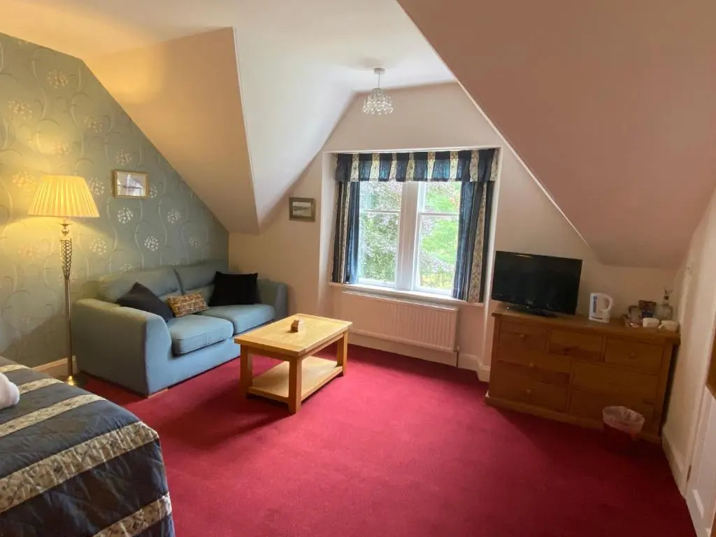 a bedroom with a bed and a couch and a window at Glenan Lodge Self Catering in Tomatin
