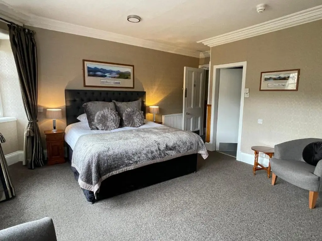 a bedroom with a bed and a couch and a chair at Invergarry Hotel in Invergarry
