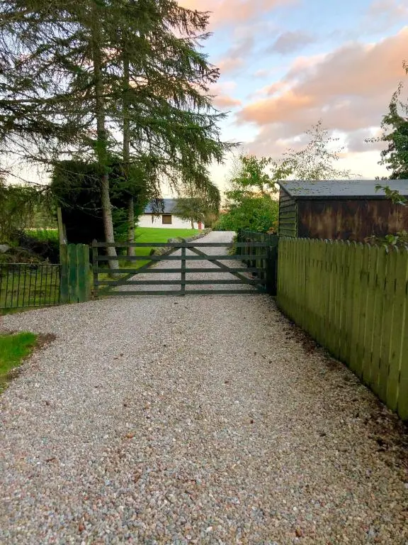 a fence and a gravel road with a gate at Belforte House Holiday Home in Inverness