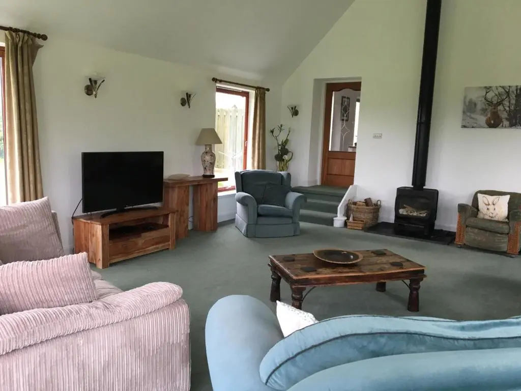 a living room with couches and a flat screen tv at Belforte House Holiday Home in Inverness