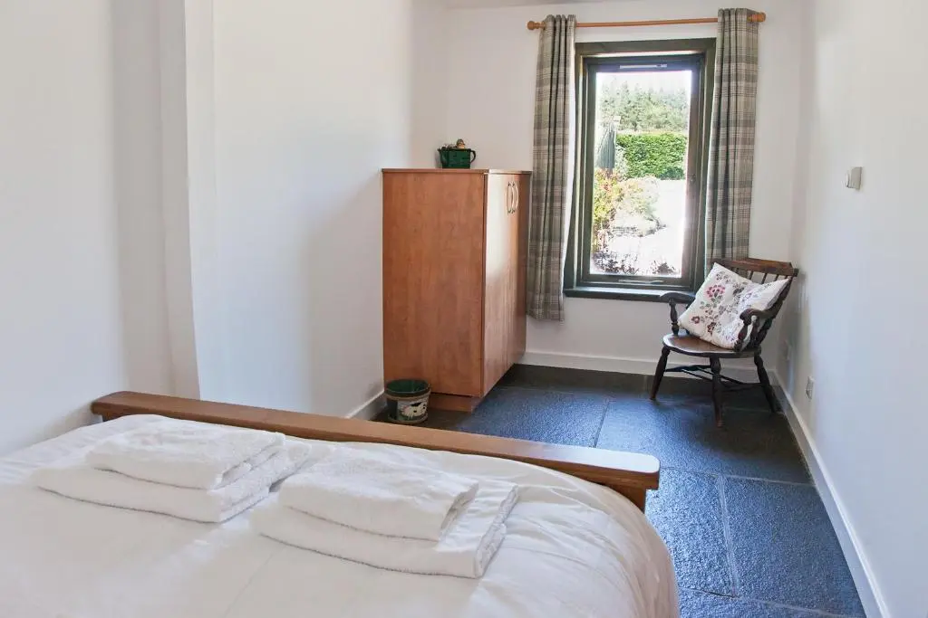 a bedroom with a bed and a chair and a window at Belforte House Holiday Home in Inverness
