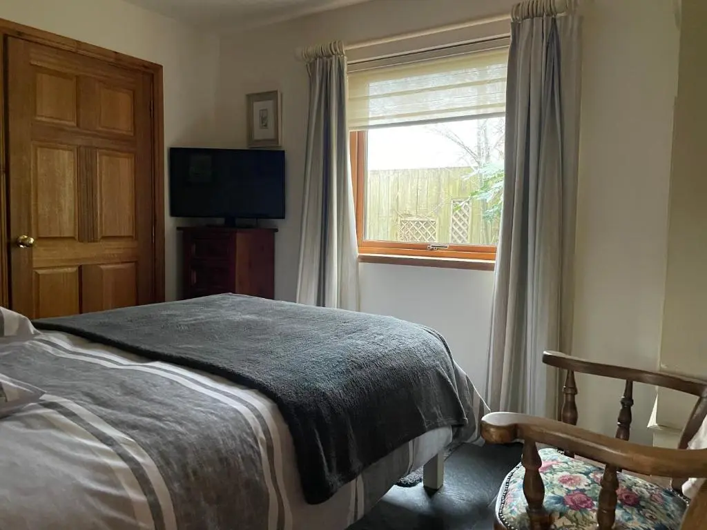 a bedroom with a bed and a window and a television at Old Mills Garden in Elgin
