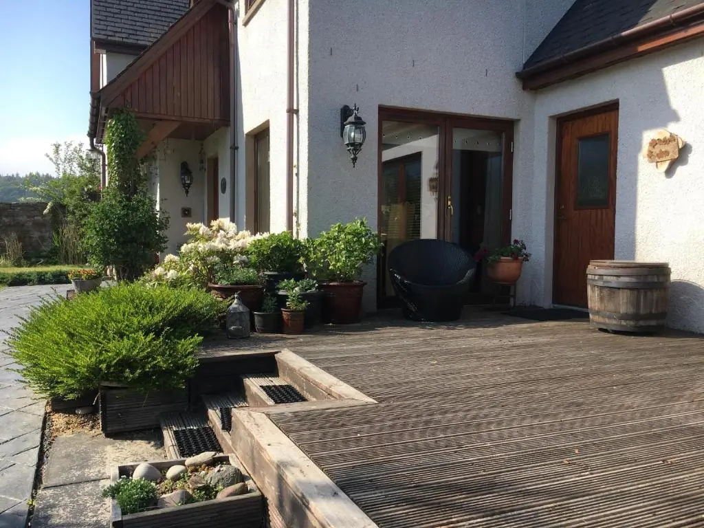 a wooden deck with potted plants in front of a house at Old Mills Garden in Elgin