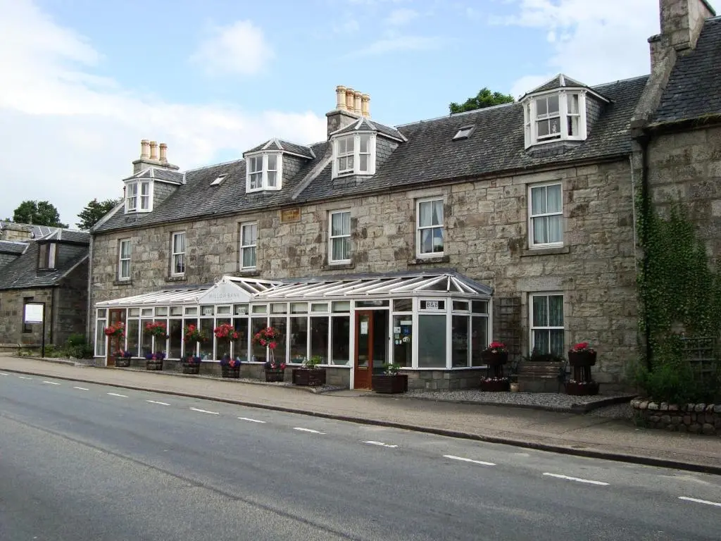 an old stone building with a greenhouse in front of it at Willowbank in Grantown on Spey