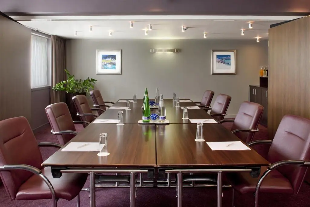 a conference room with a large wooden table and chairs at Holiday Inn Aberdeen West by IHG in Westhill