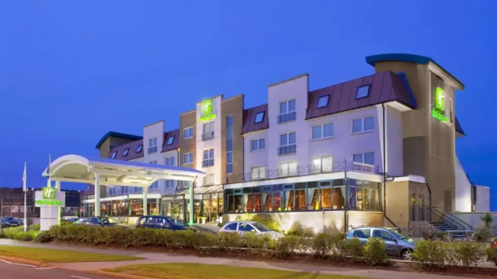 a hotel with cars parked in front of a gas station at Holiday Inn Aberdeen West by IHG in Westhill