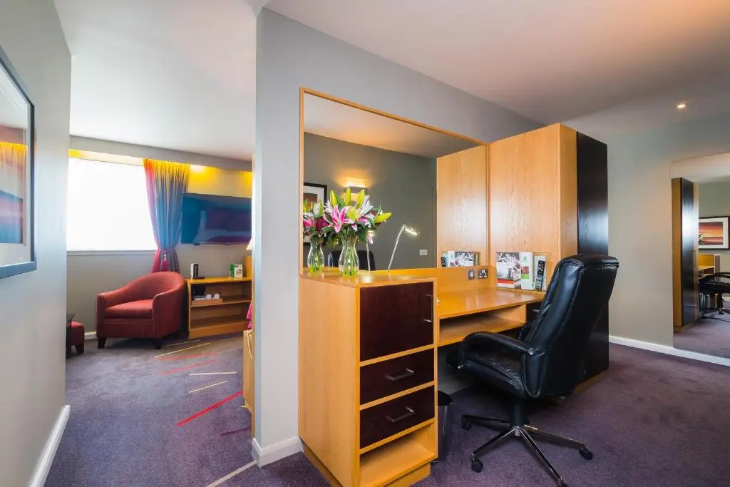 an office with a desk and a chair and a vase of flowers at Holiday Inn Aberdeen West by IHG in Westhill