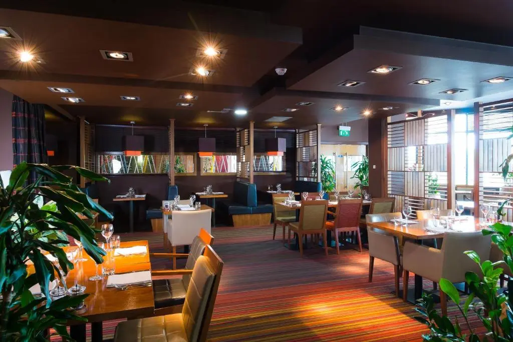 a dining room with tables and chairs and a restaurant at Holiday Inn Aberdeen West by IHG in Westhill